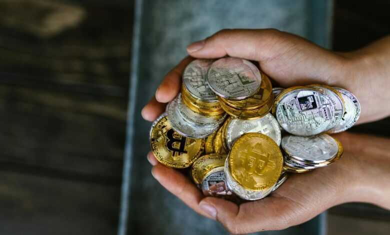 A close-up of hands holding various cryptocurrency coins, representing digital finance.