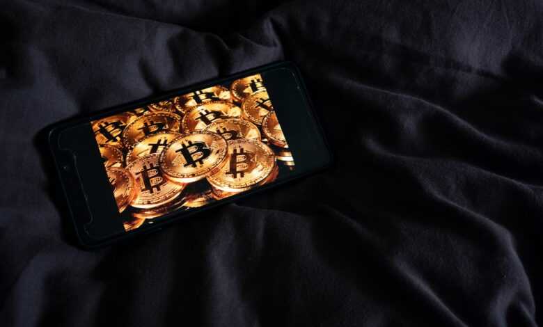 a cell phone sitting on top of a bed covered in gold coins