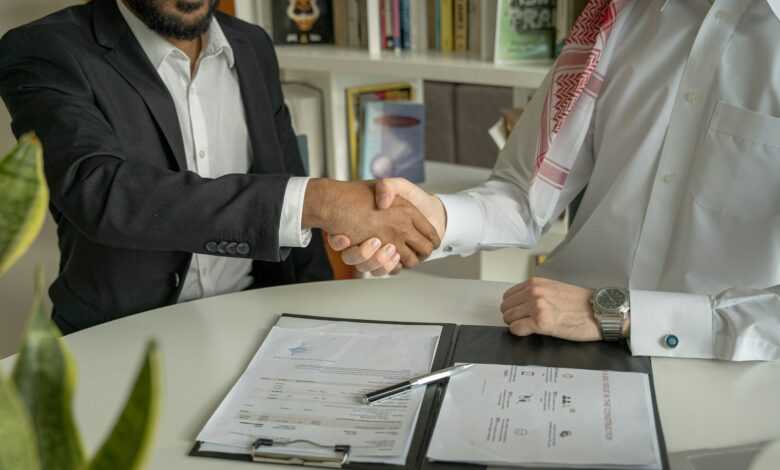 a couple of men shaking hands over a desk